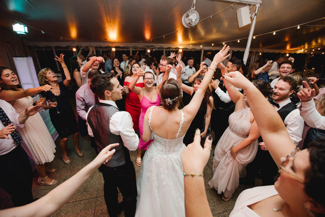 Bride, groom, and guests dancing at a wedding celebration.